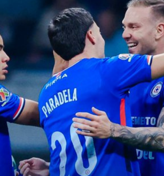 Soccer players in blue uniforms celebrate with arms around each other on the field after a play or goal.”