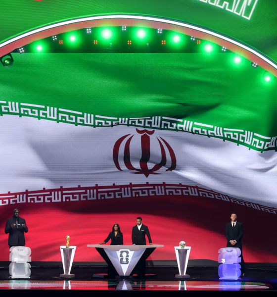 Large curved stage with Iran flag backdrop; six people stand at podiums with trophies during an awards ceremony.