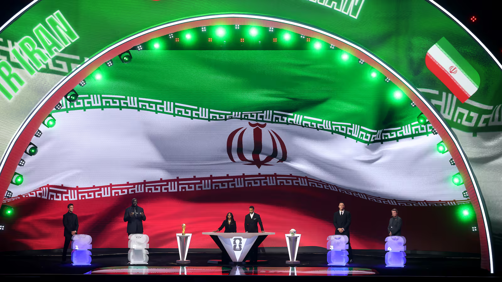 Large curved stage with Iran flag backdrop; six people stand at podiums with trophies during an awards ceremony.