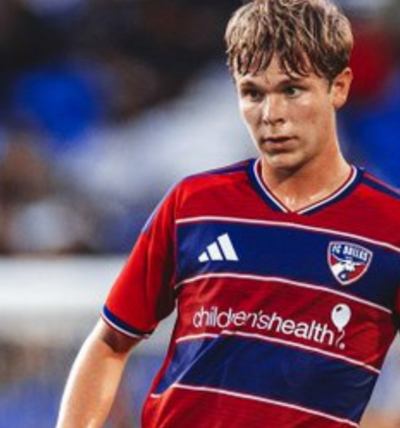 Young male soccer player in a red-and-blue jersey dribbling on the field; sponsor 'children's health' visible on the chest.