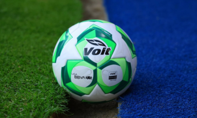Soccer ball with Volt branding resting at the edge of green grass and blue artificial turf.