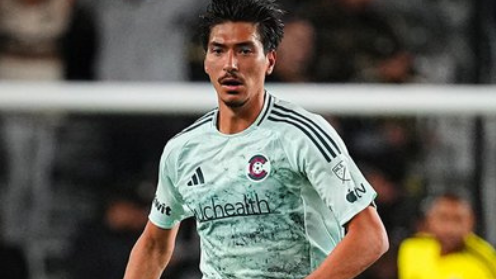 Soccer player in a pale green jersey with a Chicago club crest, running on the field during a match.