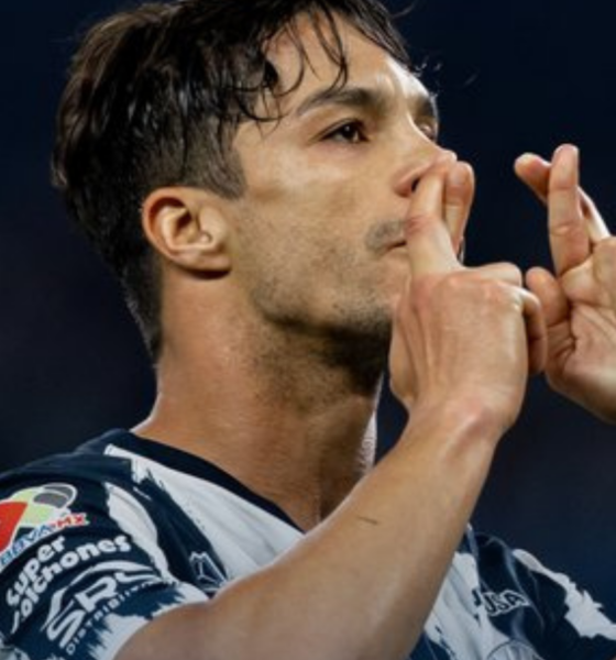 Athlete in a striped jersey kissing his fingers in a celebratory gesture on the field.