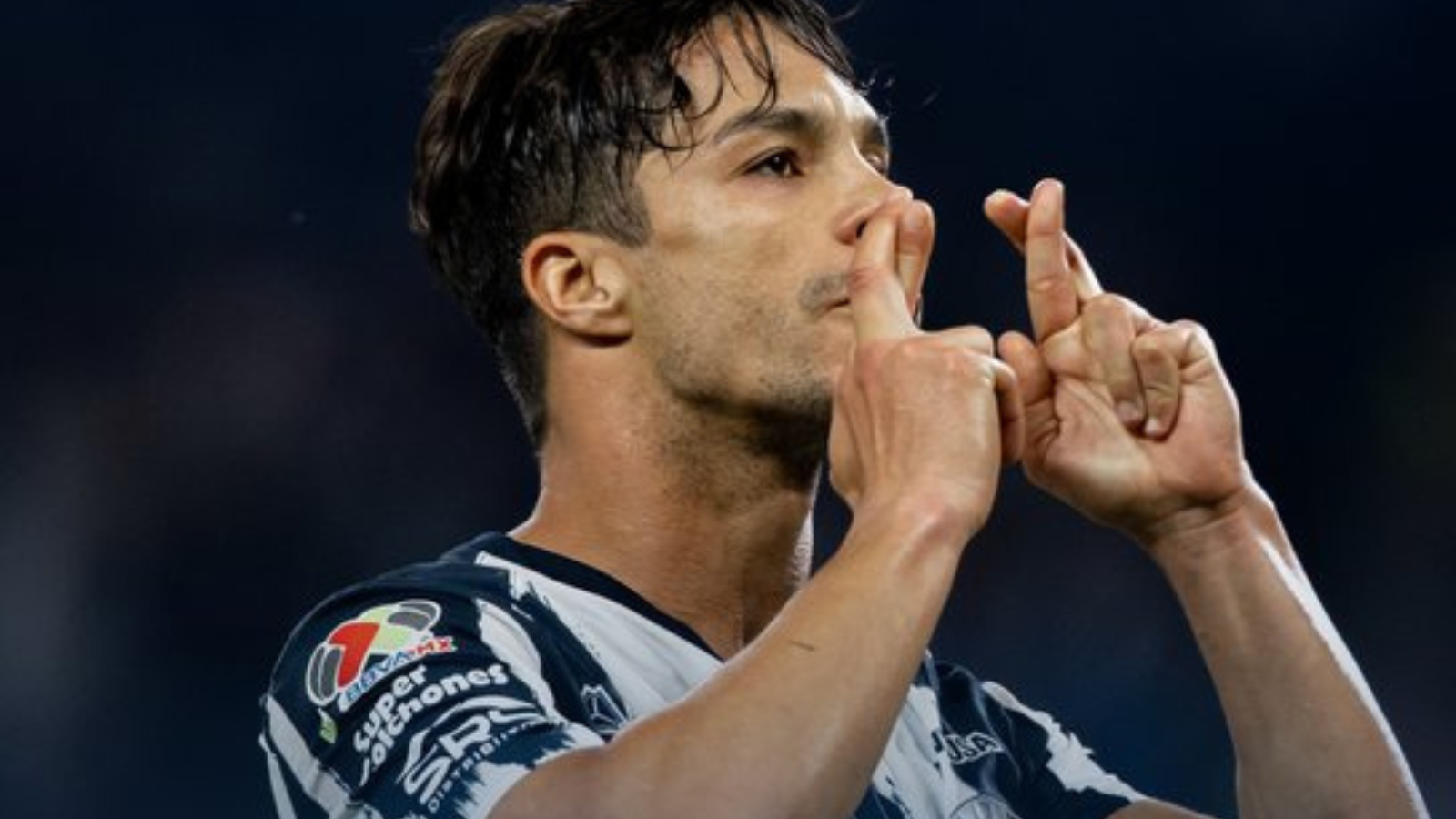 Athlete in a striped jersey kissing his fingers in a celebratory gesture on the field.