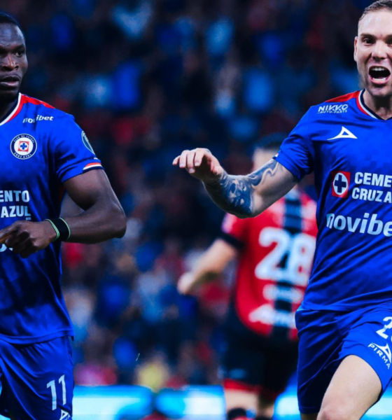 Two Cruz Azul soccer players in blue jerseys celebrate on the pitch during a match.