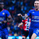 Two Cruz Azul soccer players in blue jerseys celebrate on the pitch during a match.