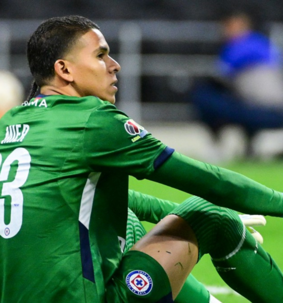 Soccer goalkeeper in a green kit with number 23 sits on the grass, knees up, during a match.