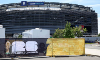 Stadium under construction with a FIFA World Cup 2026 banner and a blue 'We are New York New Jersey' sign on top.