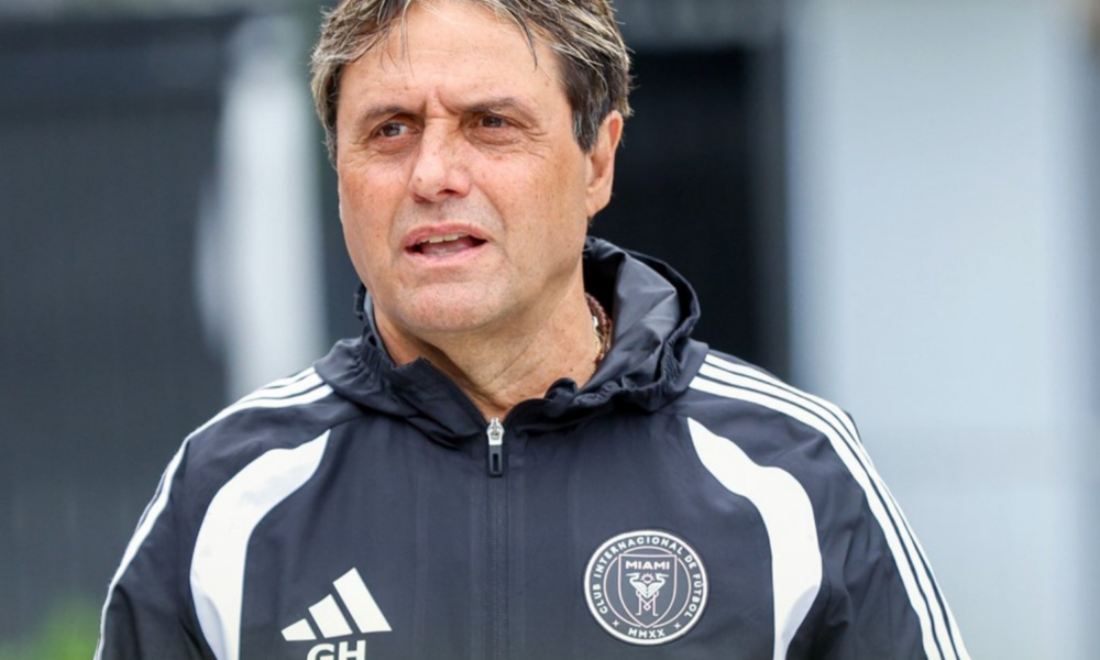 Male coach in a black-and-white training jacket with Miami FC crest, looking to the left outside.