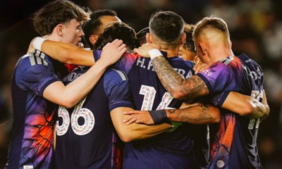 Sports team huddling in a circle, arms around each other, celebrating a win.