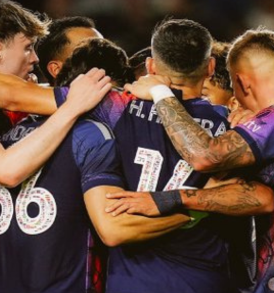 Sports team huddling in a circle, arms around each other, celebrating a win.