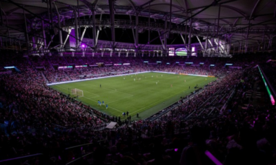 Large soccer stadium at night with players on the field and a packed crowd in the stands?