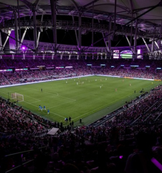 Large soccer stadium at night with players on the field and a packed crowd in the stands?