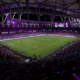 Large soccer stadium at night with players on the field and a packed crowd in the stands?