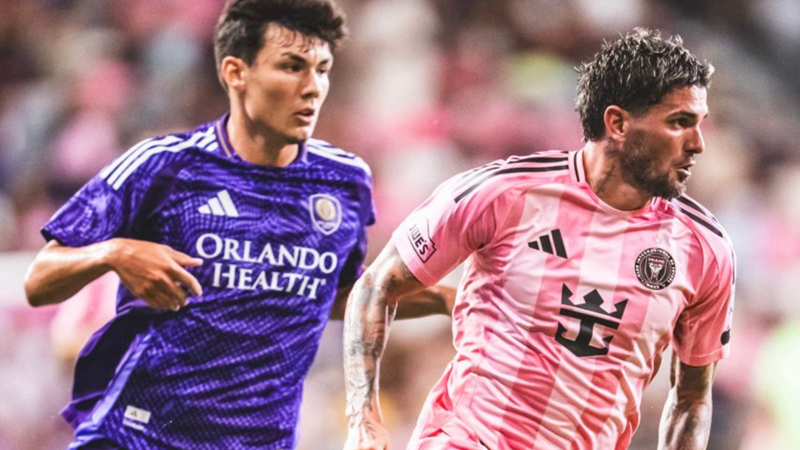 Two soccer players chase the ball on the field, one in a purple Orlando Health jersey and the other in a pink striped kit.