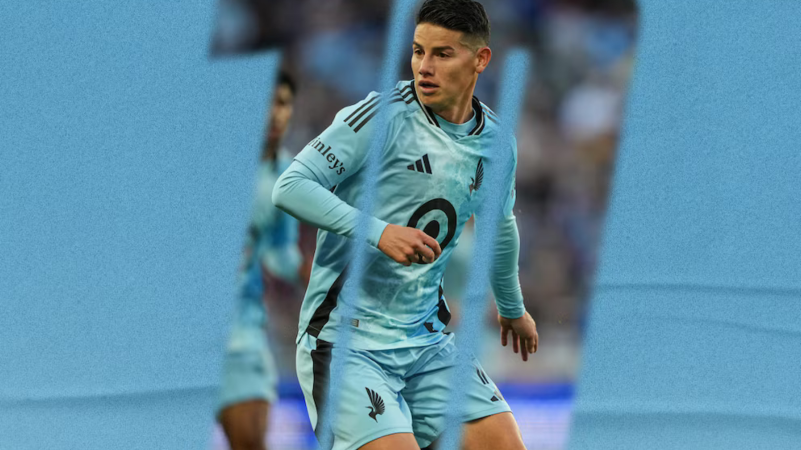 Soccer player in a light blue uniform mid-stride during a match on a blue-toned field background.