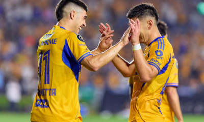 Two soccer players in yellow jerseys high-fiving on the field during a game, celebrating a moment together.
