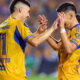 Two soccer players in yellow jerseys high-fiving on the field during a game, celebrating a moment together.