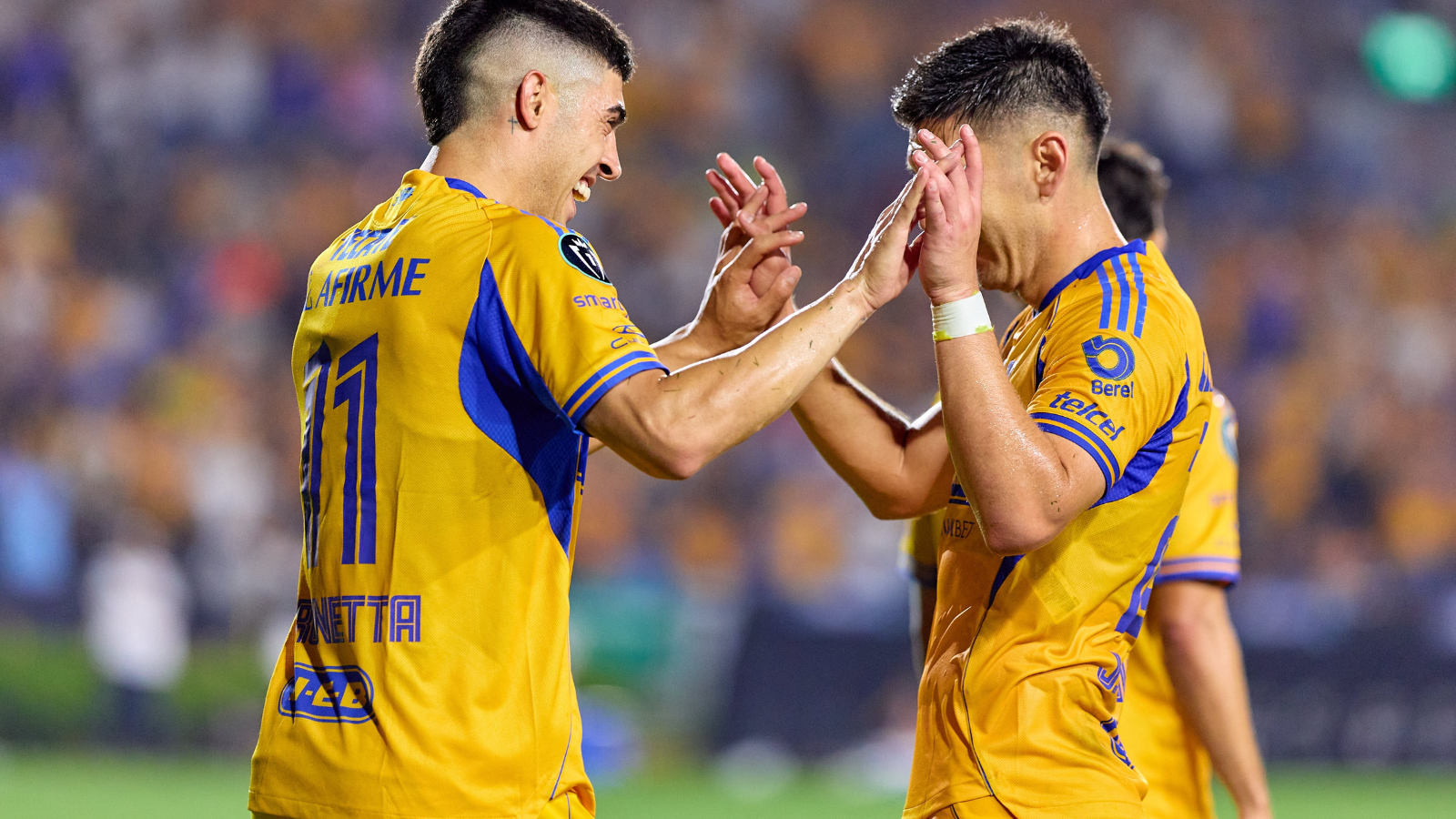 Two soccer players in yellow jerseys high-fiving on the field during a game, celebrating a moment together.