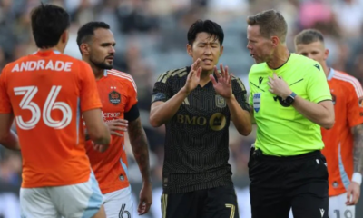 Soccer players argue with a referee on the pitch during a match.