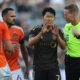 Soccer players argue with a referee on the pitch during a match.