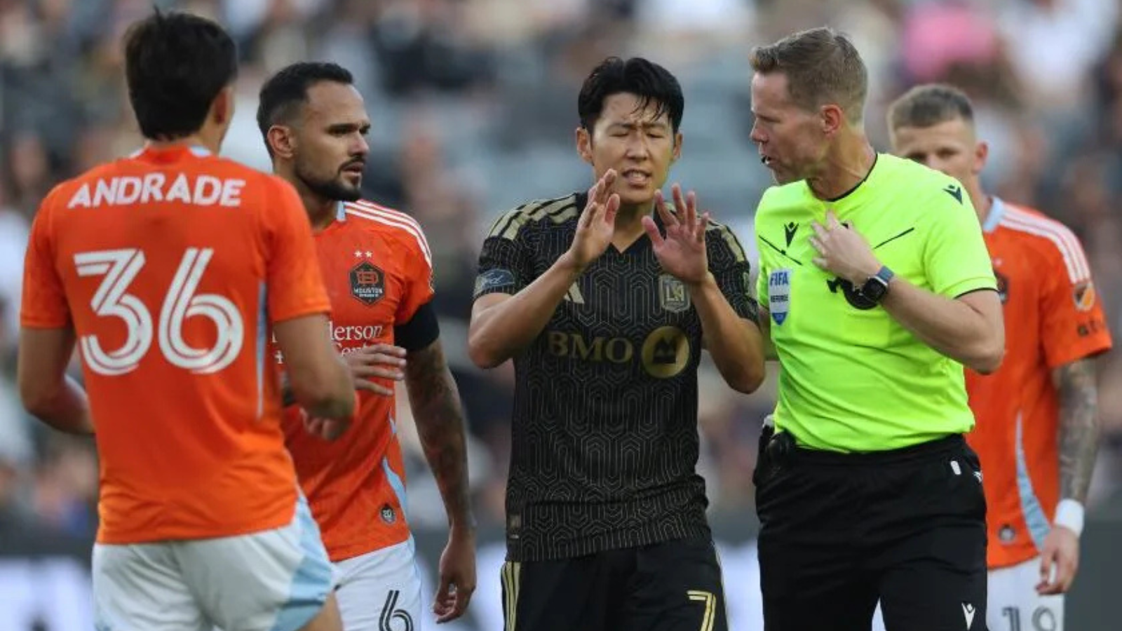 Soccer players argue with a referee on the pitch during a match.
