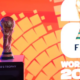 Trophy on a pedestal labeled 'WINNER'S TROPHY' against an orange geometric backdrop, with FIFA World Cup 2026 branding to the right.