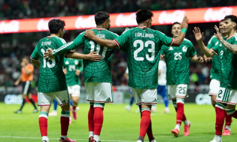 Soccer players in green jerseys celebrate with arms around each other on the field.