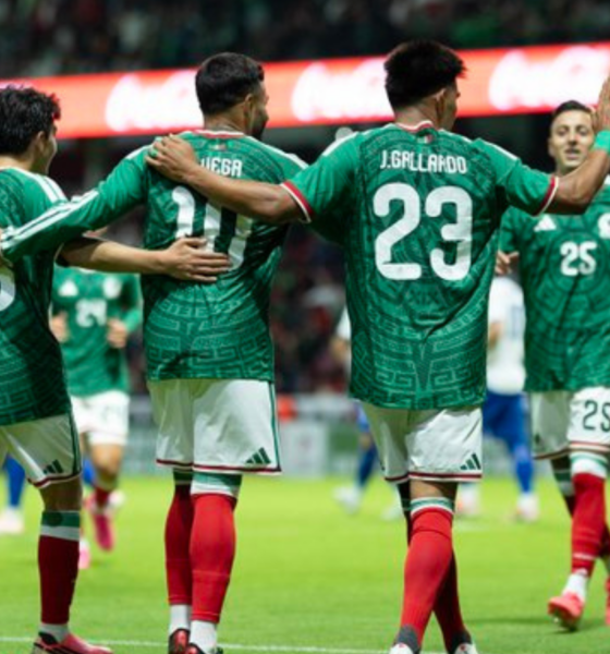 Soccer players in green jerseys celebrate with arms around each other on the field.