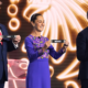 Three adults on a brightly lit stage hold black cards labeled USA, MEXICO, and CANADA in front of a swirling golden backdrop.