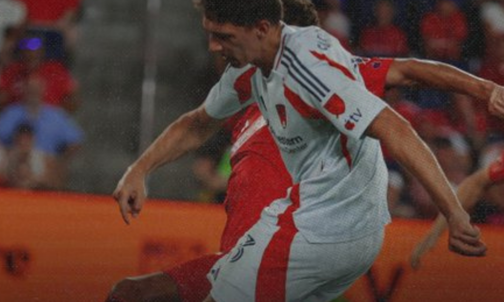 Soccer player in a white and red kit striking a kick during a match